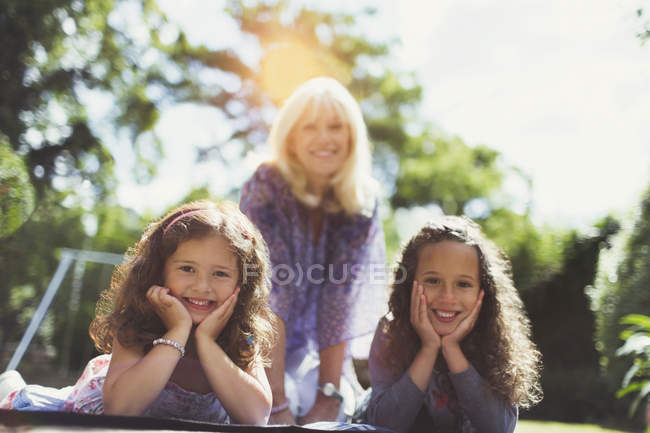 Портрет усміхненої бабусі з онуками-близнюками в парку — стокове фото