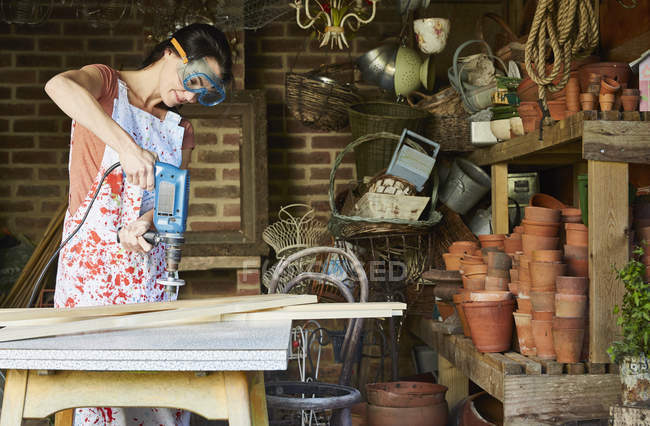 Mujer usando lijadora de poder en taller - foto de stock