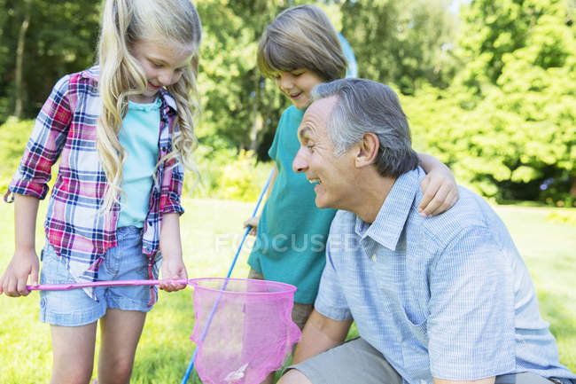 Happy man and grandchildren playing outdoors — Stock Photo