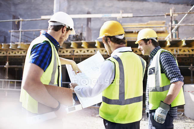 Bauarbeiter und Ingenieur überprüfen Baupläne auf Baustelle — Stockfoto