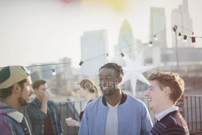 Young men talking at rooftop party — Stock Photo