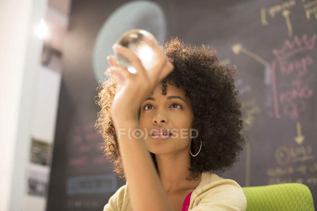 Femme d'affaires examinant boule de cristal dans le bureau — Photo de stock