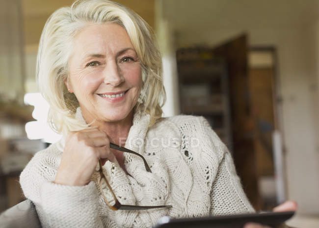 Портрет усміхненої старшої жінки в светрі тримає цифровий планшет — стокове фото