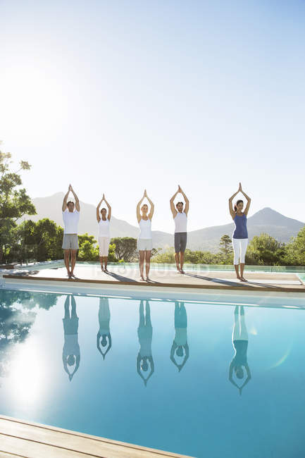 Junge attraktive Menschen praktizieren Yoga am Pool — Stockfoto