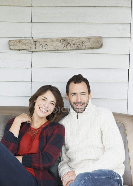 Retrato sonriente pareja en el porche de abajo? The Shack? signo - foto de stock