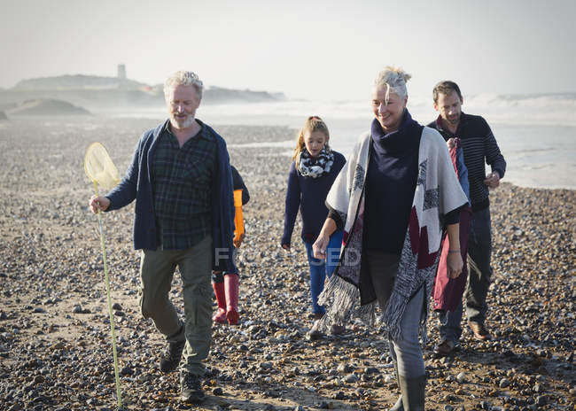 Famille multi-génération marchant sur une plage ensoleillée — Photo de stock