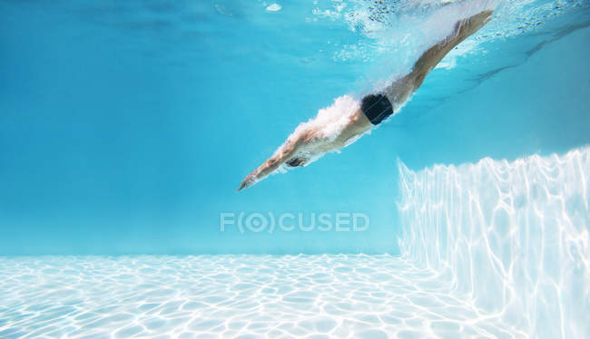 Вид сбоку на молодого человека, ныряющего в бассейн — стоковое фото