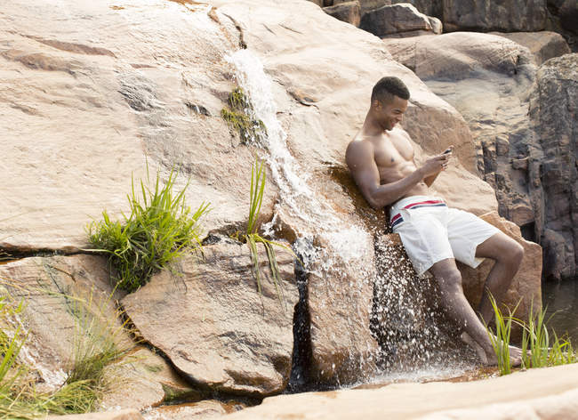 Людина використовує мобільний телефон біля водоспаду — стокове фото