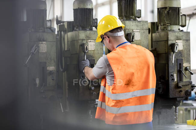 Trabalhador em vestuário de trabalho de protecção que utiliza máquinas na fábrica — Fotografia de Stock