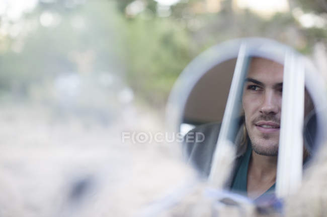 Reflection of man's face in side view mirror — Stock Photo