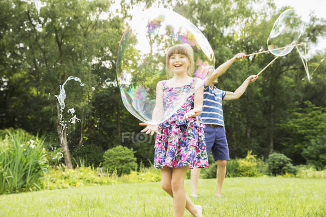 Children playing with bubbles in backyard — Stock Photo