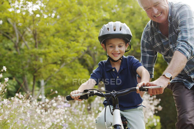 Grandfather teaching grandson to ride bicycle — Stock Photo