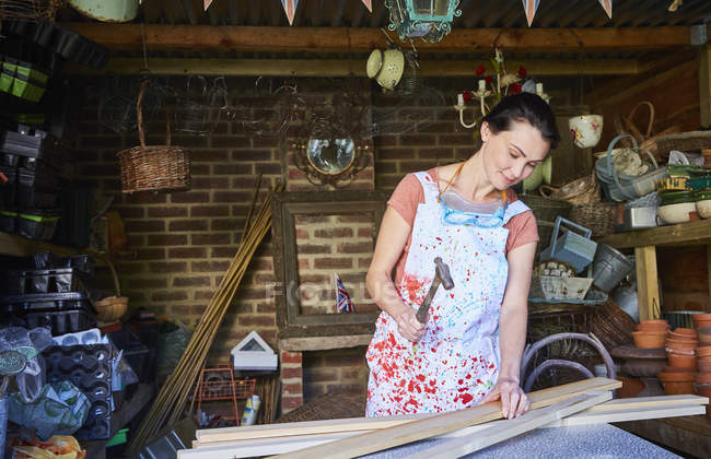 Woman hammering wood boards in workshop — Stock Photo