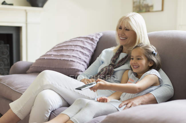 Grand-mère et petite-fille regardant la télévision sur le canapé du salon — Photo de stock