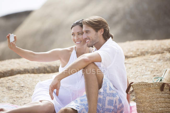 Casal tirando fotos juntos na praia de areia — Fotografia de Stock