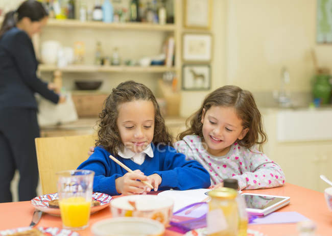 Девочки делают домашнее задание за завтраком — стоковое фото