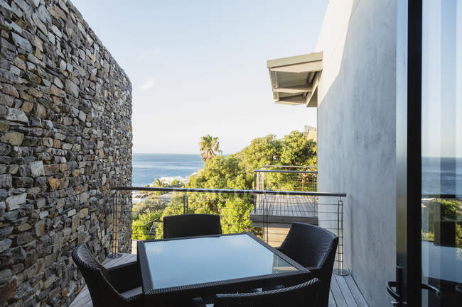 Стіл і стільці на розкішному балконі з видом на океан — стокове фото