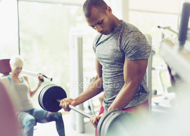 Focused man doing barbell biceps curls at gym — Stock Photo