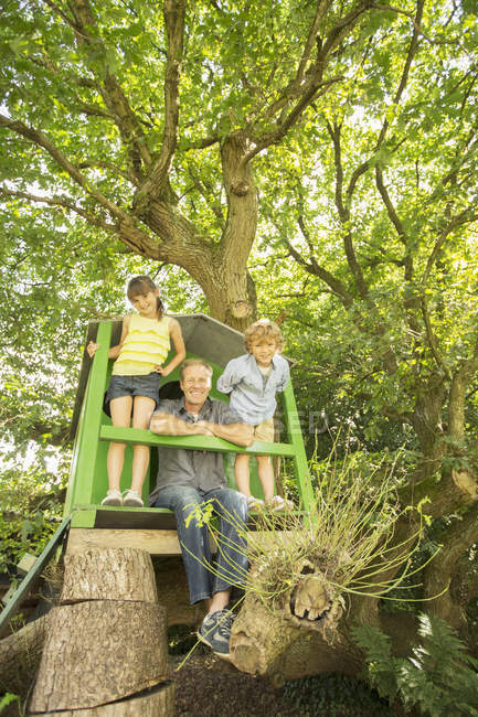 Heureux père et enfants jouant dans la cabane dans les arbres — Photo de stock