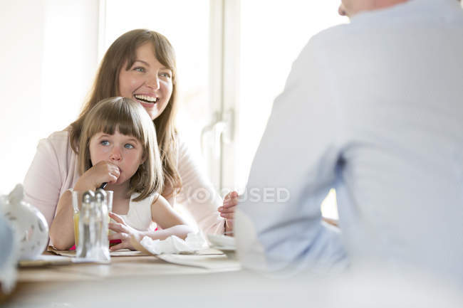Familie sitzt drinnen am Cafétisch — Stockfoto