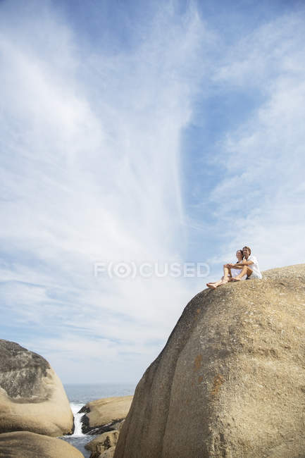 Paar sitzt auf Felsformation am Strand — Stockfoto