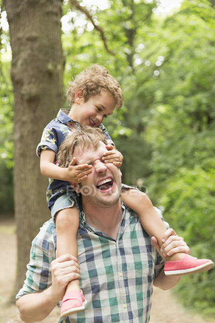 Playful son covering fathers eyes in woods — Stock Photo