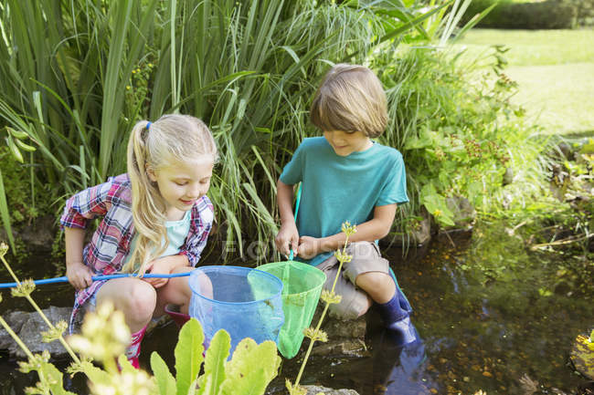 Niños felices que pescan juntos en el estanque - foto de stock