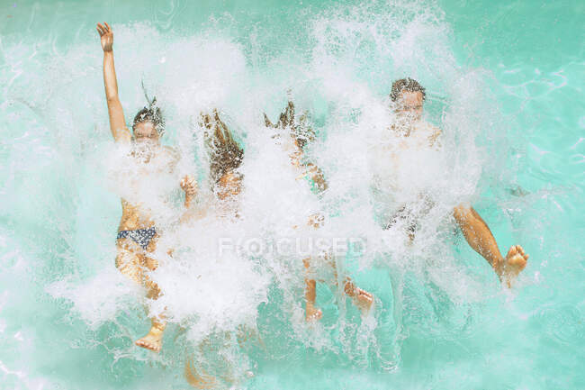 Family jumping into swimming pool — Stock Photo