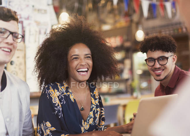 Riendo amigos con portátil en la cafetería - foto de stock