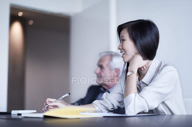 Усміхнена бізнес-леді робить нотатки на зустрічі — стокове фото