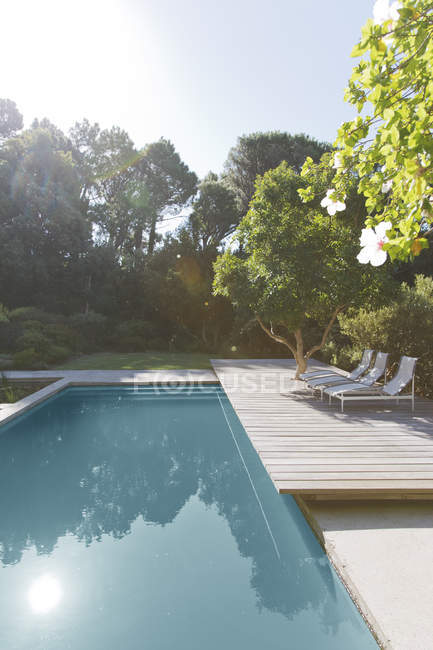 Terrasse en bois et chaises longues près de la piscine — Photo de stock