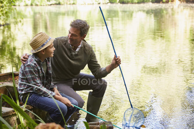 Padre e hijo pescando con redes en estanque - foto de stock