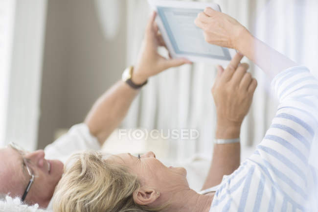 Couple plus âgé utilisant une tablette numérique sur le lit — Photo de stock