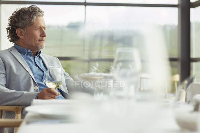Homem pensativo bebendo vinho branco na sala de jantar da adega — Fotografia de Stock