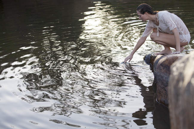 Mulher mergulhando mão no lago — Fotografia de Stock