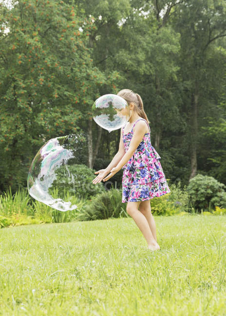 Menina feliz brincando com bolhas no quintal — Fotografia de Stock