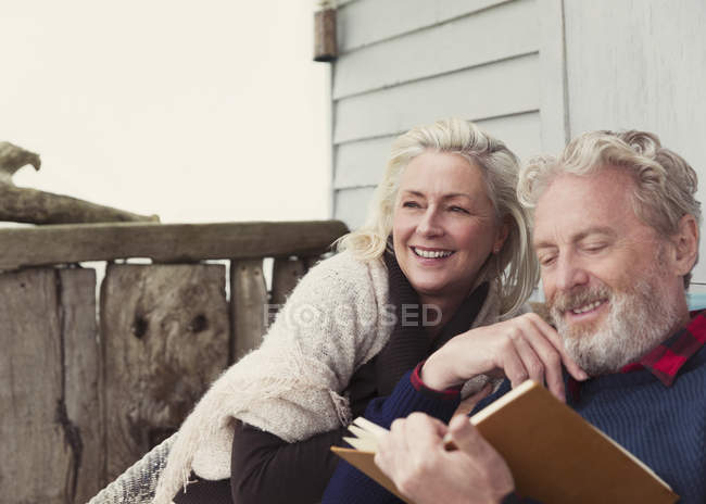 Lächelndes Seniorenpaar liest Buch auf der Terrasse — Stockfoto