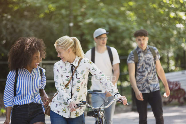 Friends walking with bicycle in park — Stock Photo