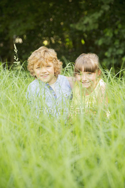 Feliz vhildren jogar na grama alta — Fotografia de Stock