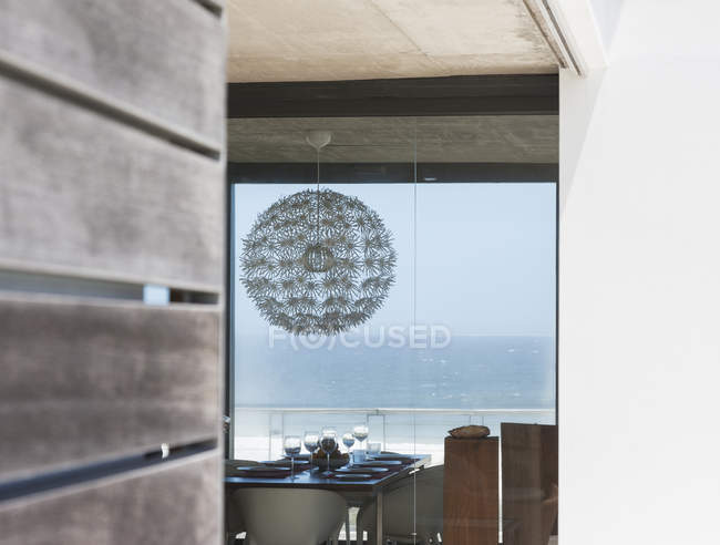 Chandelier above dining table overlooking ocean — Stock Photo