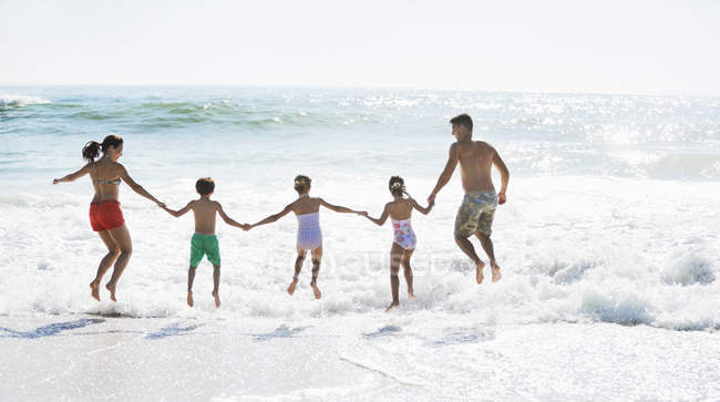 Família saltando no surf na praia — Fotografia de Stock