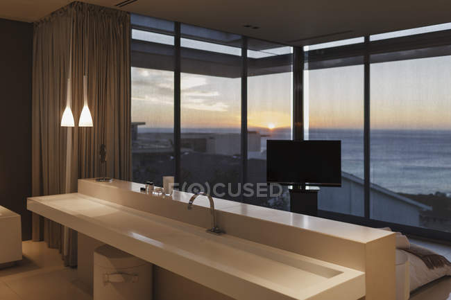 Modernes Waschbecken im Schlafzimmer mit Blick auf den Ozean bei Sonnenuntergang — Stockfoto