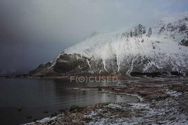 Snow covered mountains above cold lake, Norway — Stock Photo