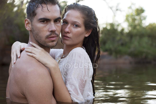 Portrait of serious couple hugging in river — Stock Photo