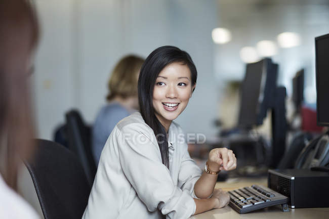 Mujer de negocios sonriente hablando con un colega en el cargo - foto de stock