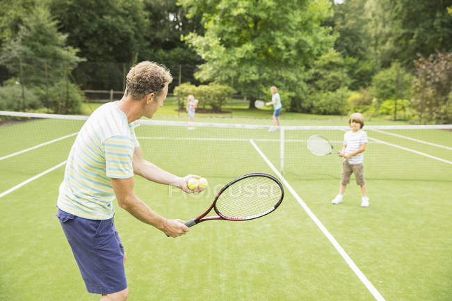 Родина грає в теніс на трав'яному корті — стокове фото
