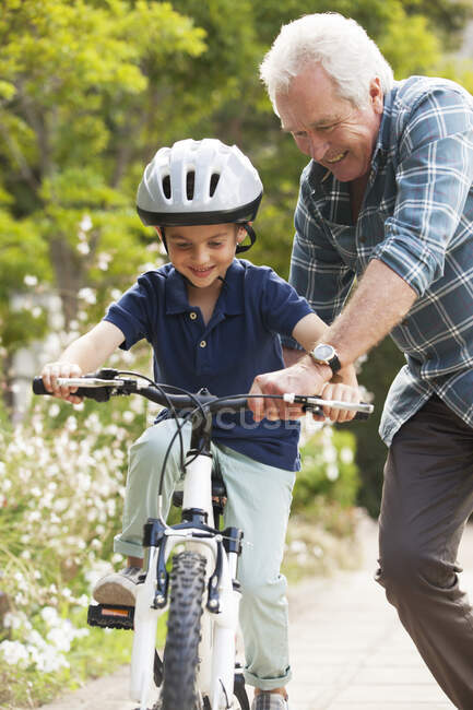 Abuelo enseñando nieto a montar en bicicleta - foto de stock