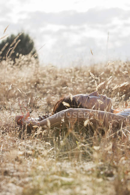 Femme sereine dormant dans un champ rural ensoleillé — Photo de stock