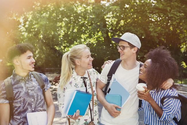 College students with books and coffee walking in park — Stock Photo