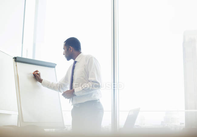 Businessman writing on whiteboard — Stock Photo